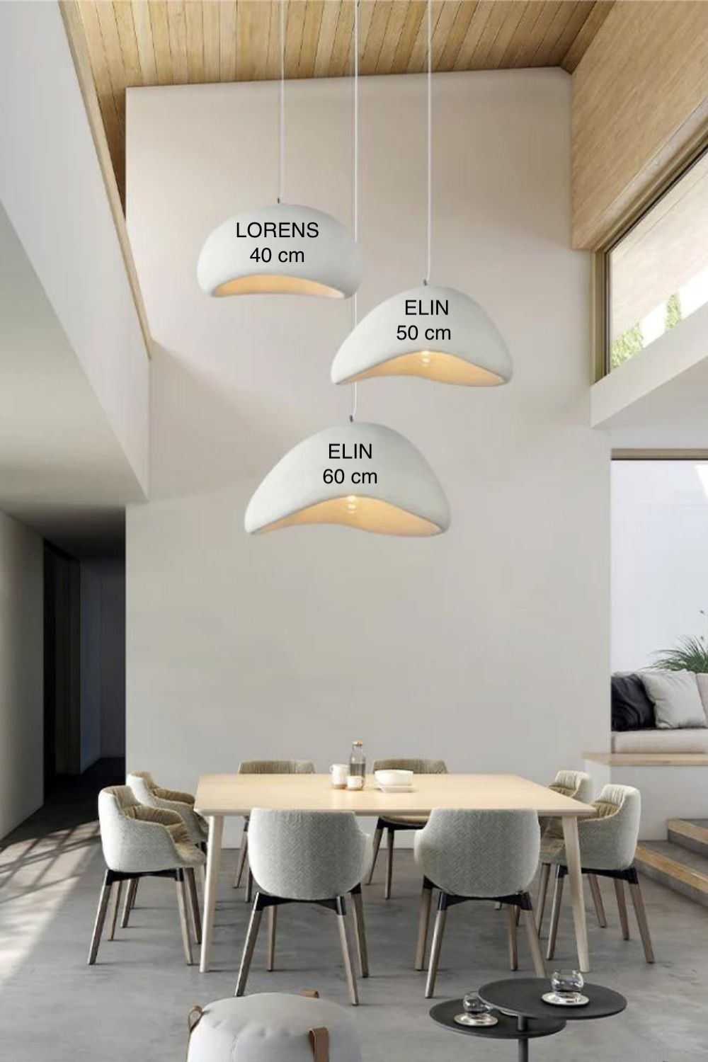 salle à manger contemporaine et lumineuse avec haut plafond sur lequel sont accrochés trois grosses suspensions luminaires design indiquant les dimensions